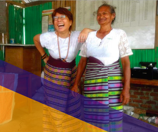 Two women wearing skirts of ethnic weaves laughing