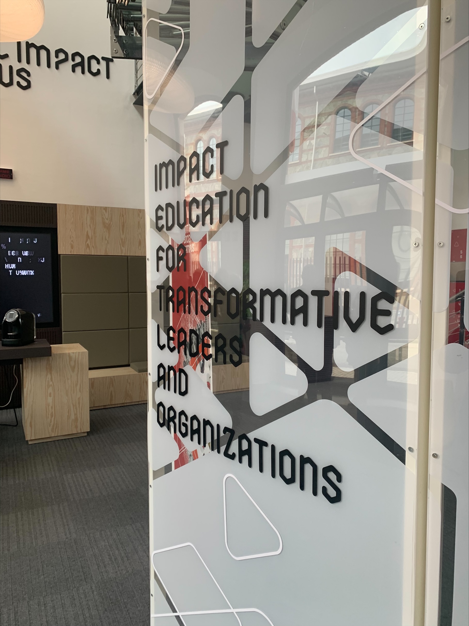 Zdjęcie przedstawia biały baner z czarnym napisem "Impact education for transformative leaders and education"