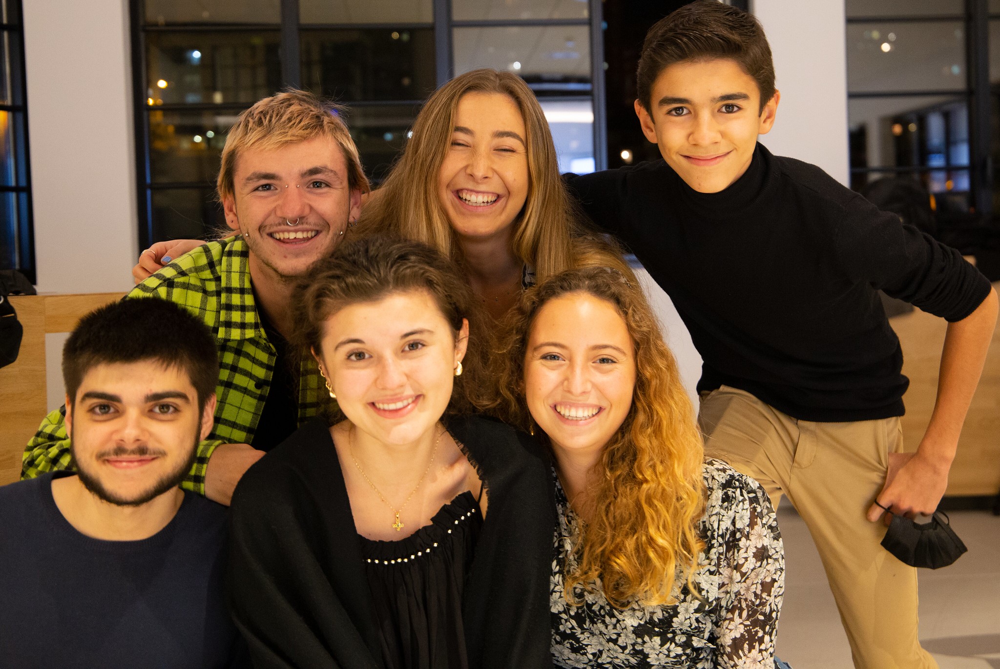 Six young changemakers posing for the camera in two rows; background of a room
