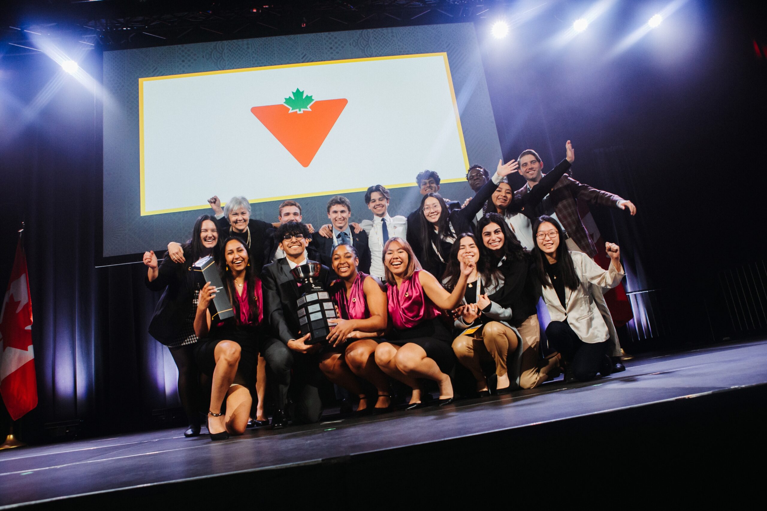 Group of people on a stage in two rows smiling at the camera