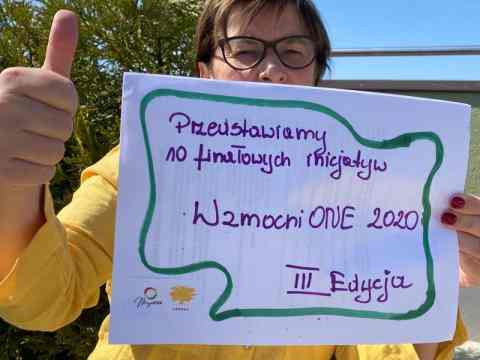 women in yellow shirt with banner: Przedstawiamy 10 finałowych inicjatyw Wzmocnione2020