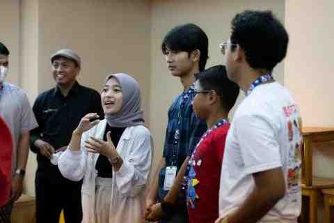 One girl talking and three boys look at her