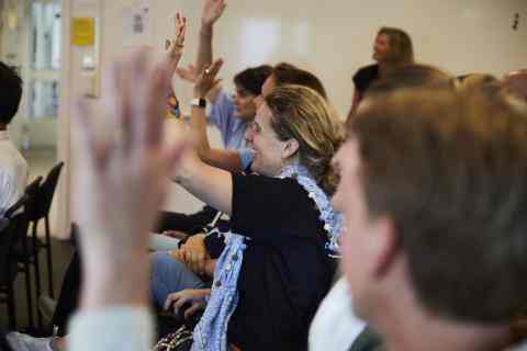Adults raising their hands in a classroom