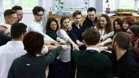 A group of young people standing in a circle putting their hands together