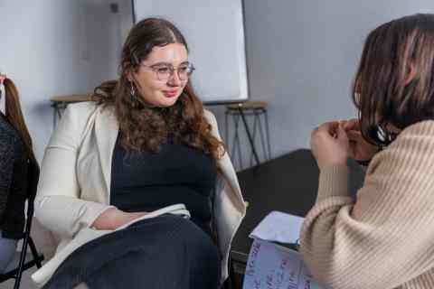Two young woman sitting facing each other and talking