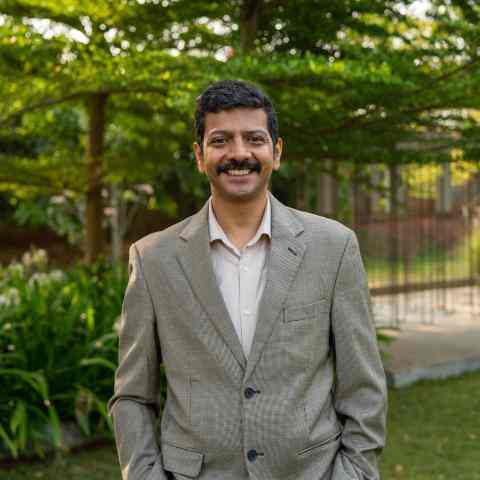 Headshot of Senior Fellow Mekin Maheshwari. He is an Indian man with a mustache and short, dark hair. He is wearing a gray suit.