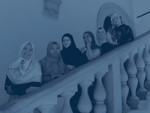6 girls wearing hidjab standind on the stairs and smiling.