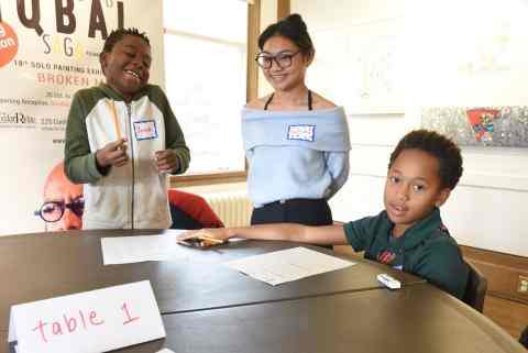 Three students at a table smiling at the camera
