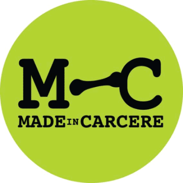 Circle with lime green fill; big bold letter M and C, and a wrench tool in between the M and the C; below in smaller bolded letters: Made in Carcere
