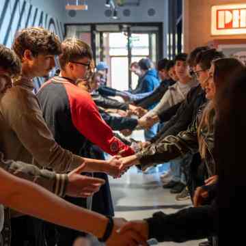 Photo of group of youth standing in two rows and reaching out their hands to each other 