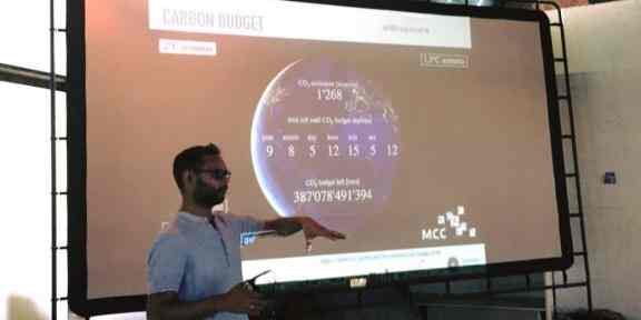 Zdjęcie przedstawia Srirama Kuchimanchi wygłaszającego prezentację. Na slajdzie za nim znajdują się dane dotyczące emisji CO2.