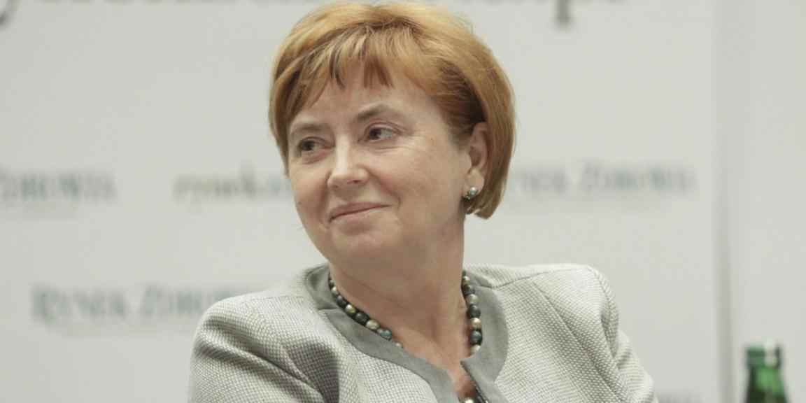 Zdjęcie uśmiechniętej Elżbiety Szwałkiewicz w szarej marynarce i niebieskim naszyjniku.