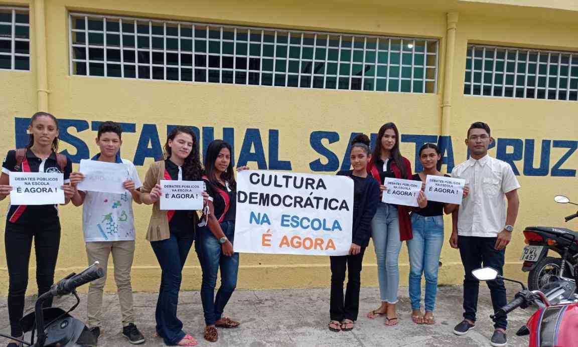 Grupo de jovens seguram cartazes sobre cultura democrática