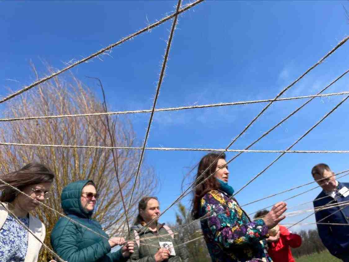73 / 5 000 A group of people standing outside holding strings that connect them like a net.