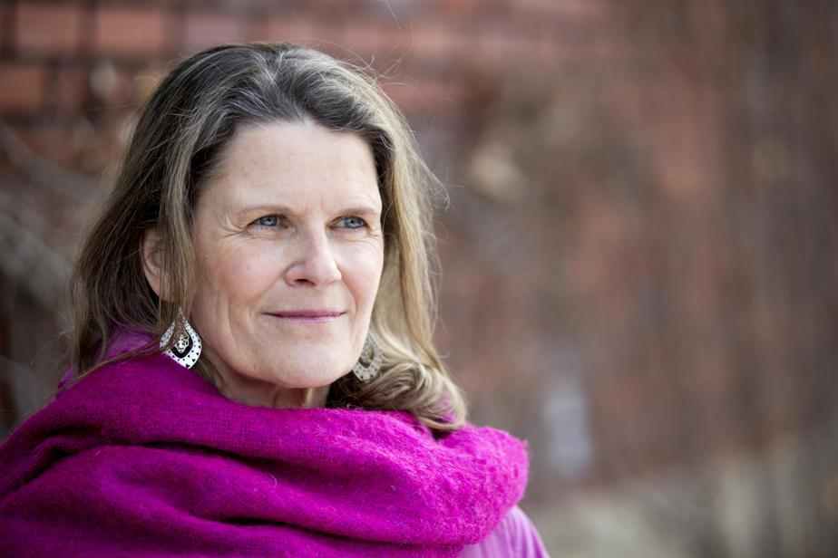 Photo of Canada Fellow Rachel Kiddell-Monroe. Photo of a person with longer brown hair and lighter skin smiling to the right of the camera. Dressed in a pink scarf; background of a brick wall.