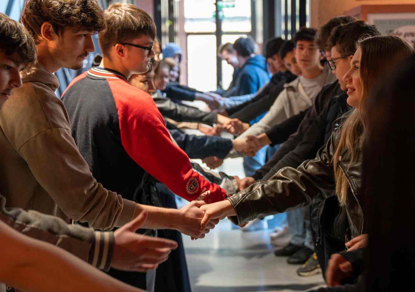 Photo of group of youth standing in two rows and reaching out their hands to each other 