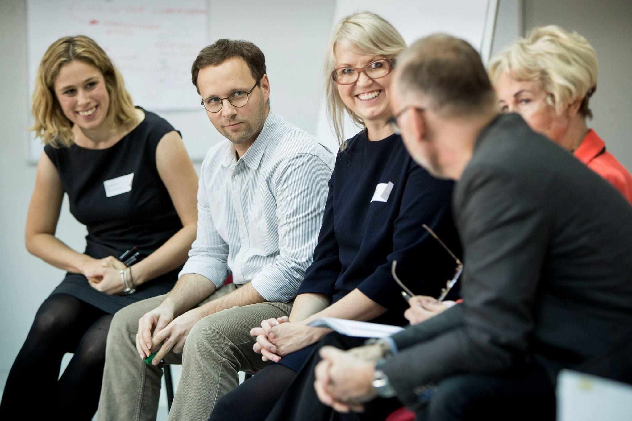 persons sitting in the circle, smiling 