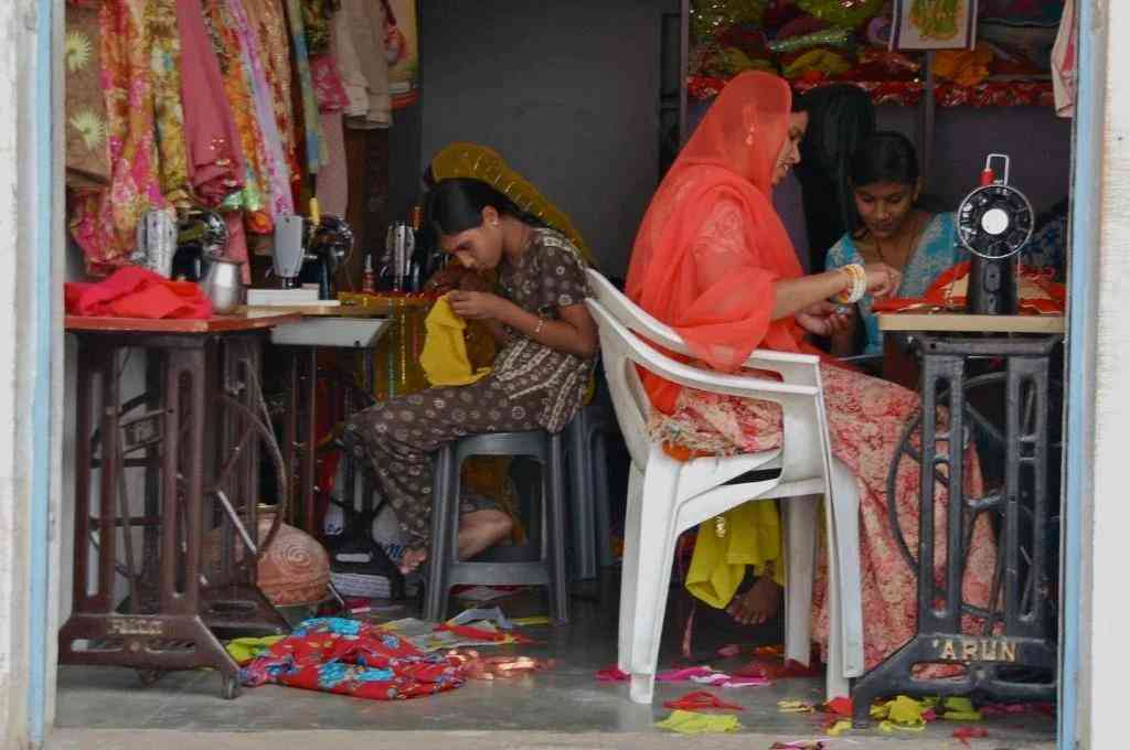 women-sitting-on-chairs-on-a-fabric-shop-working-on-stitching-clothes