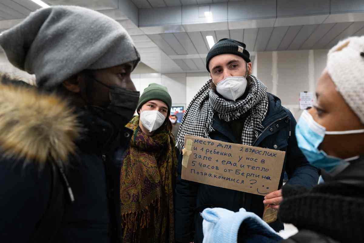 People in a group talking in winter clothes as well as COVID masks on. Sign in Ukrainian