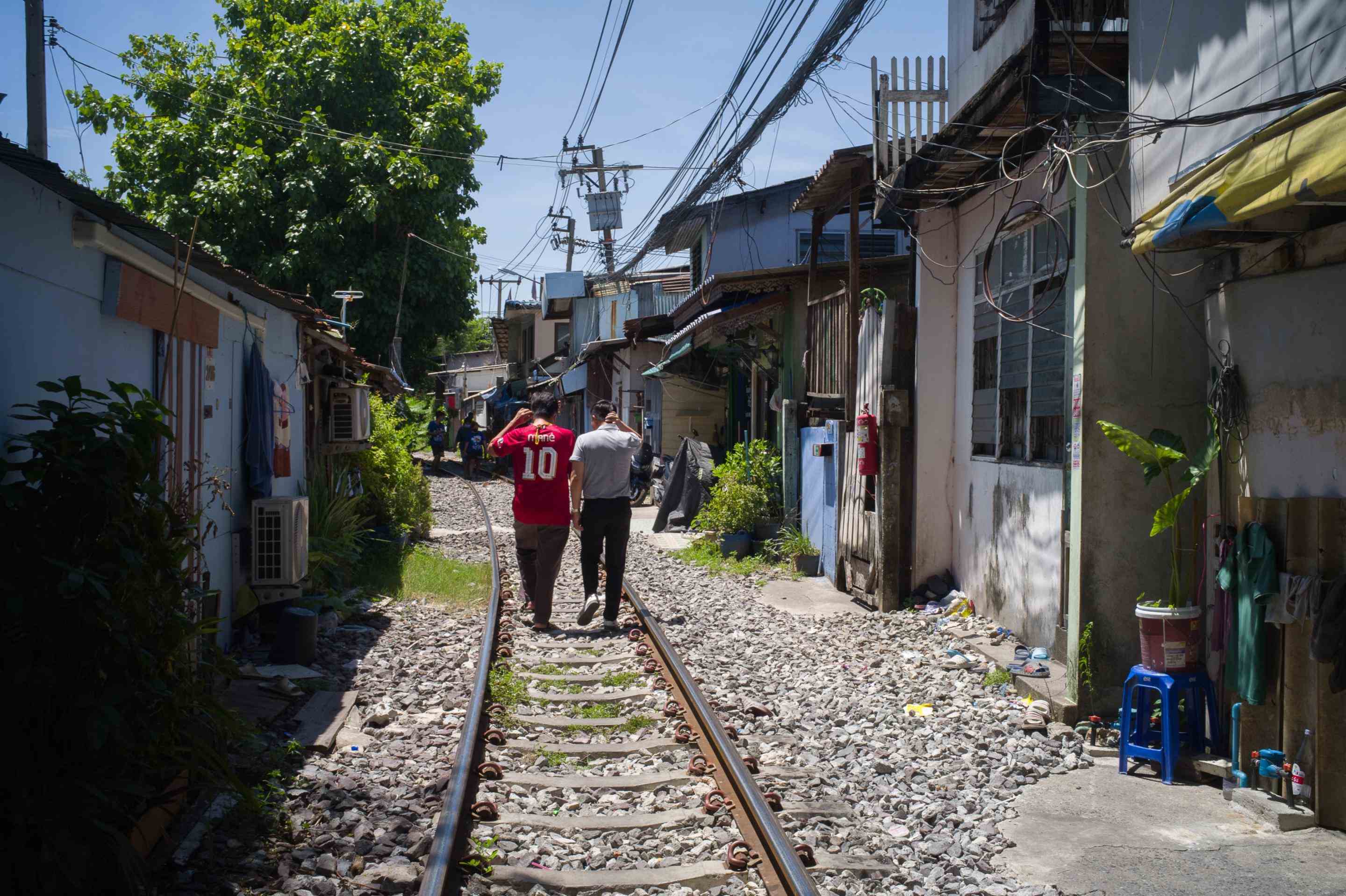 Two people walking down a railroad behind a number of houses