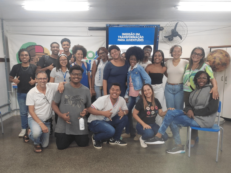 Grupo de jovens reunidos em uma sala posando para a foto. Algumas estão em pé e outras estão agachadas