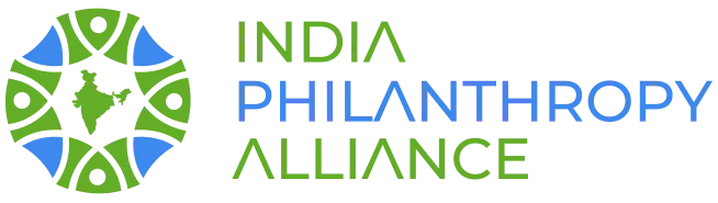 Logo of the India Philanthropy Alliance. On the left is a circular emblem made of green and blue shapes forming an abstract pattern with a silhouette of India in the center. To the right, the organization’s name is written in stylized uppercase letters: ‘India’ and ‘Alliance’ in green, and ‘Philanthropy’ in blue.