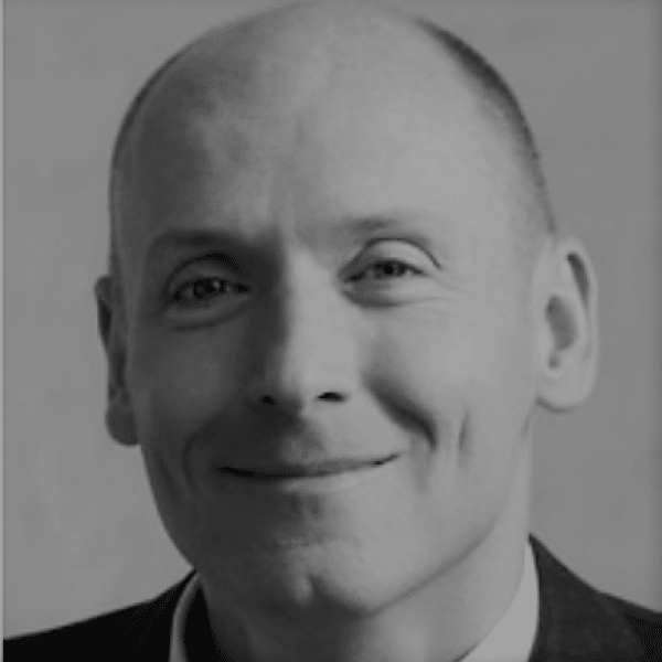 Czarno-biały portret uśmiechającego się Piotra Pawłowskiego