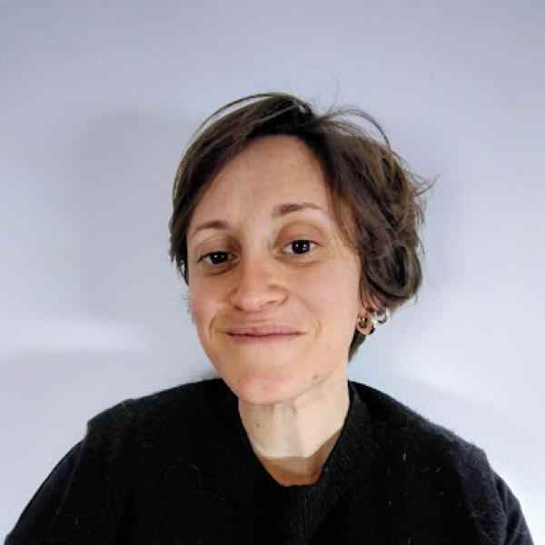 Headshot of Teresa Seabra Pereira. Person with short hair smiling at the camera; background a light wall