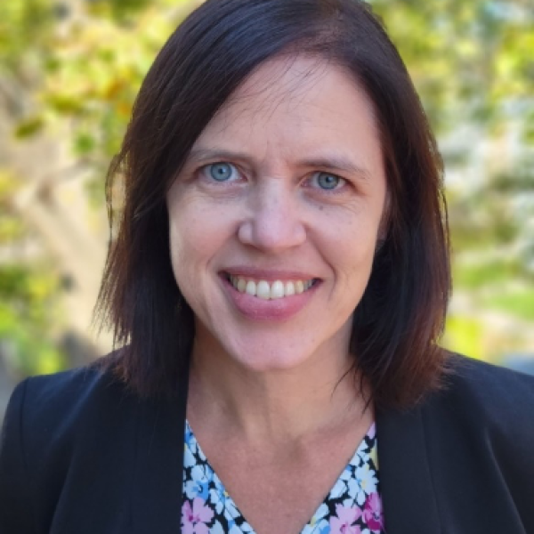 Photo of Claire Fallender, Leadership group member of Ashoka's Global Youth Strategy. Person with lighter skin and shoulder length brown hair smiling at the camera; dressed in a professional blue suit top and flower pattern blouse