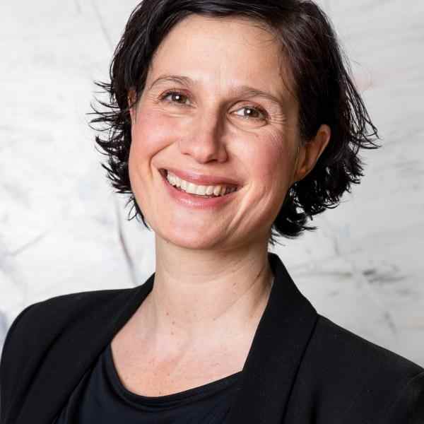 Woman with short hair and dark blazer smiling at the camera 