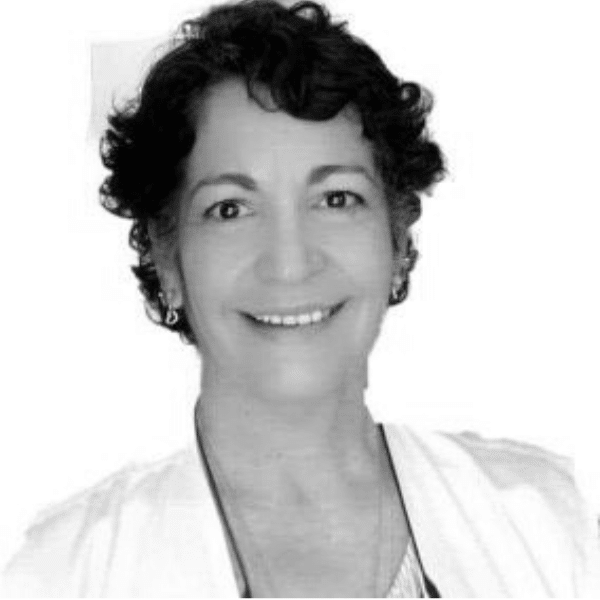 Foto em preto e branco de Fátima, mulher branca com cabelos curtos e encaracolados. Ela sorri para a foto e usa uma blusa branca