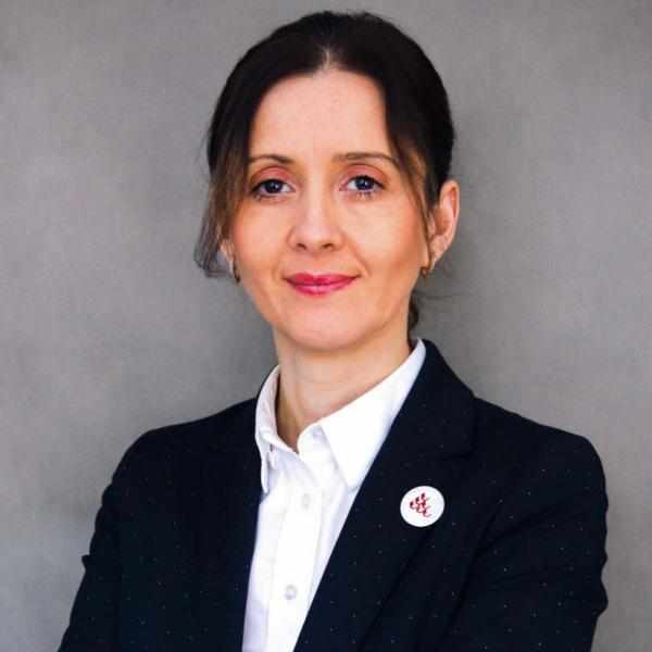 Zdjęcie przedstawia dr Marię Mazur, profesor WSPA w garniturze i białej koszuli na szarym tle.