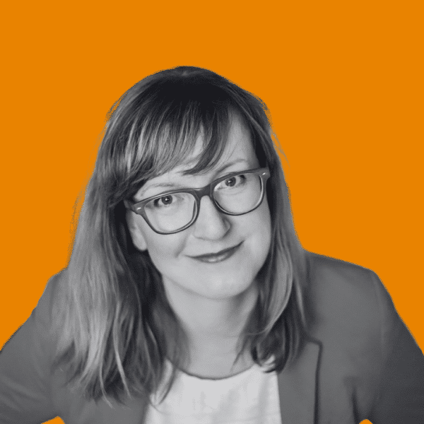 Woman looking directly into the camera, wearing glasses, smiling