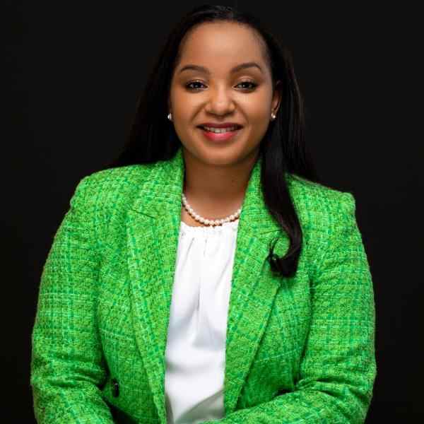 Doris wearing a green blazer on a black background