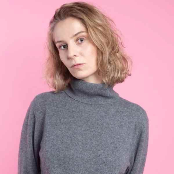 Photo of a woman in grey jumper on a pink background