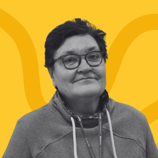 Grayscale portrait of a woman with short, hair, wearing glasses and a casual sweatshirt, facing the camera. The background is yellow with abstract curved lines.