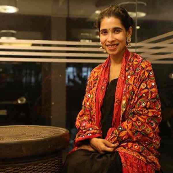 Ashoka Fellow Alina Alam. She is an Indian woman with long black hair wearing a red coat.