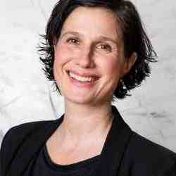 Woman with short hair and dark blazer smiling at the camera 