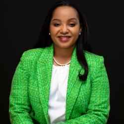 Doris wearing a green blazer on a black background