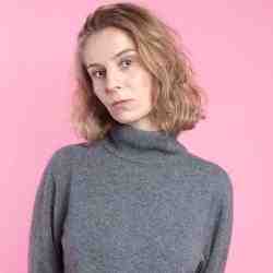 Photo of a woman in grey jumper on a pink background