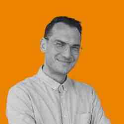 Man in glasses, wearing a shirt smiling to the camera