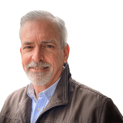 Headshot of Peter Mortifee, ASN Member. Person with light grey hair and goatee smiling at the camera. Dressed in a jacket and collared shirt; no background