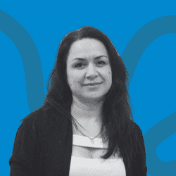 Grayscale portrait of a woman with long dark hair, wearing a white blouse and black cardigan, facing the camera. The background is blue with abstract curved lines.