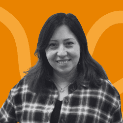 Grayscale portrait of a woman with dark hair, wearing a checkered shirt, smiling, facing the camera. The background is orange with abstract curved lines