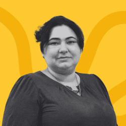 Grayscale portrait of a women with dark hair tied in a bunr, wearing dark blouse, facing the camera. The background is yellow with abstract curved lines