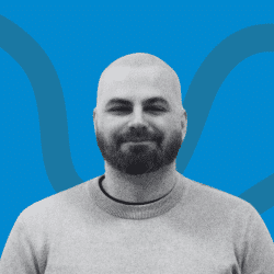 Portrait of a man with beard, smiling to the camera.