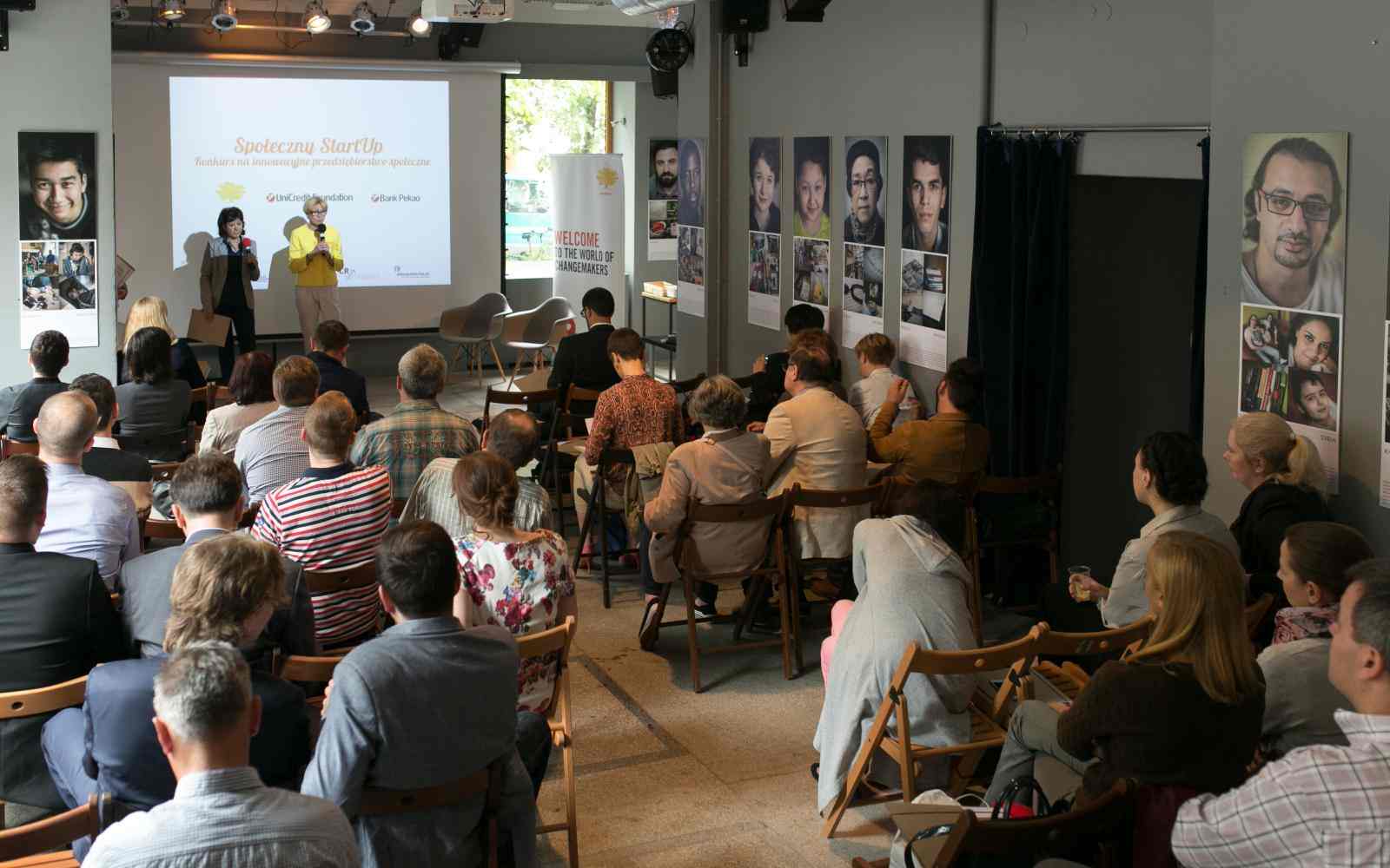 frontal setting, group of people listening, two women at the stage