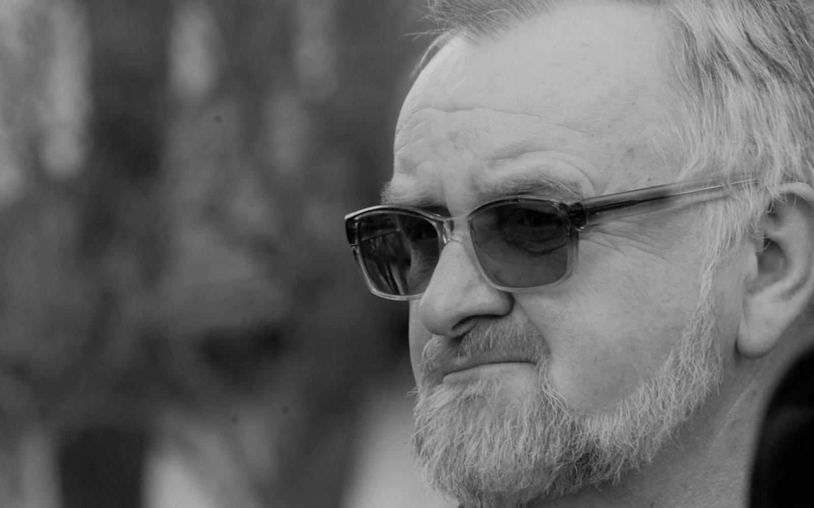 Czarno-biały portret Krzysztofa Liszcza w okularach przeciwsłonecznych.