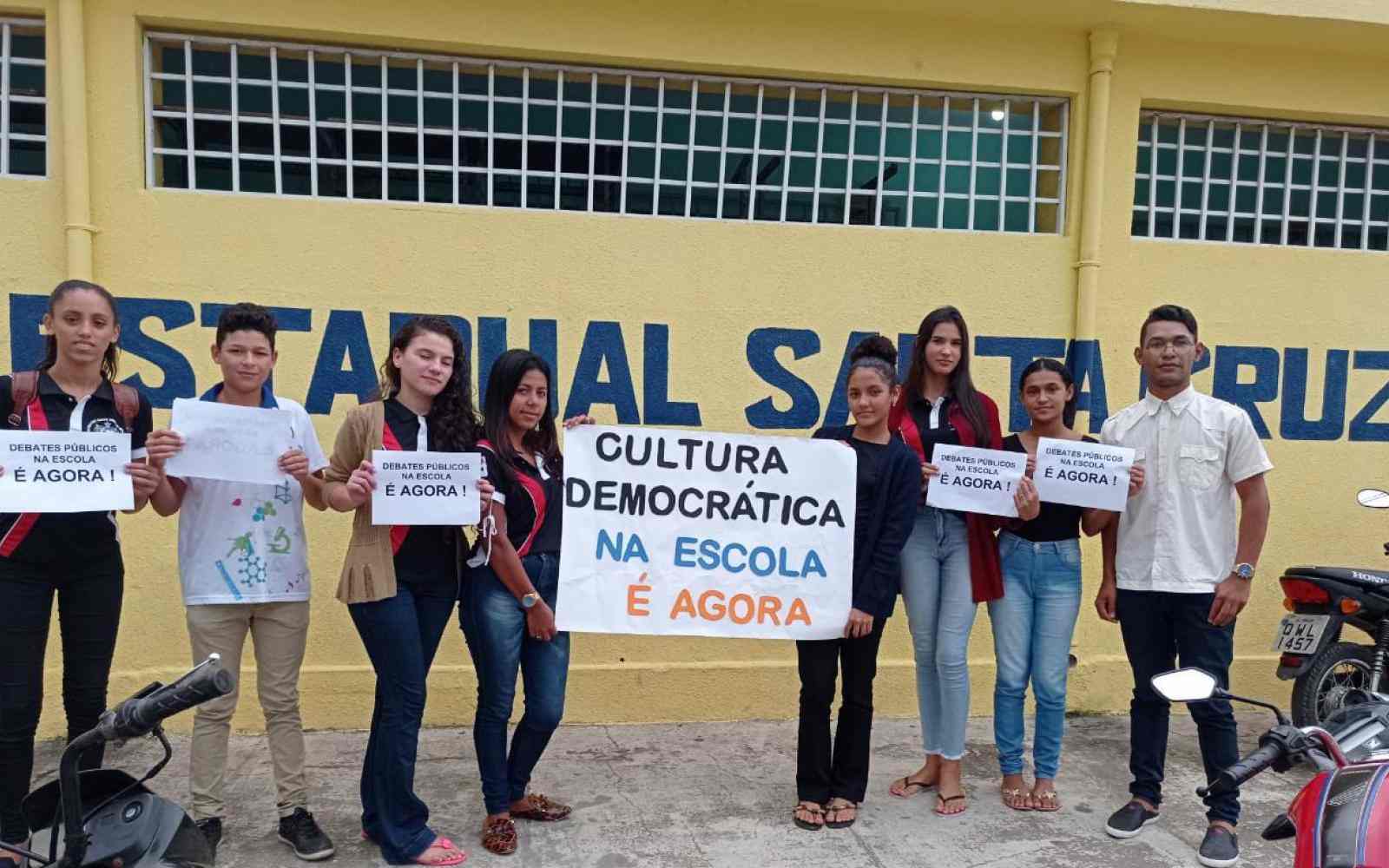 Grupo de jovens seguram cartazes sobre cultura democrática