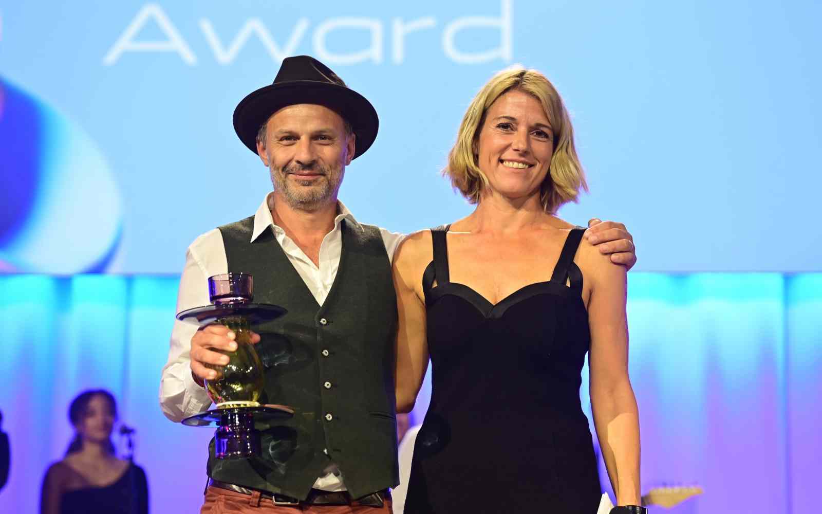 Fellow Jonas Staub posing with presenter and holding a trophy at award ceremony